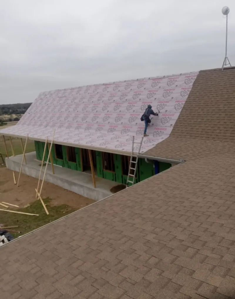 Worker preparing underlayment for a metal roof installation in Kennett